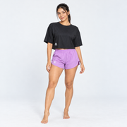 Modelo de cuerpo completo con Blusa Over Crop 1 negra de Grama combinada con shorts lilas
