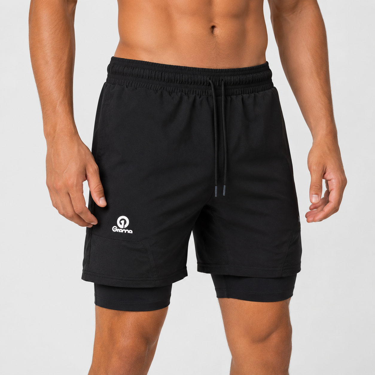 Pantaloneta deportiva negra para hombre con licra interna, pretina ajustable y logo Grama reflectivo, vista frontal.