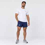 Modelo con pantaloneta Ruman azul de Grama, combinada con camiseta deportiva blanca, vista de cuerpo completo.
