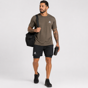 Hombre usando pantaloneta deportiva negra Grama con camiseta deportiva café, tenis negros y bolso de gimnasio.