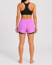 Short Lotus rosa para mujer, vista posterior con pretina elástica y capa interior negra visible.