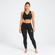Mujer usando top deportivo Niza negro Grama con leggings negros